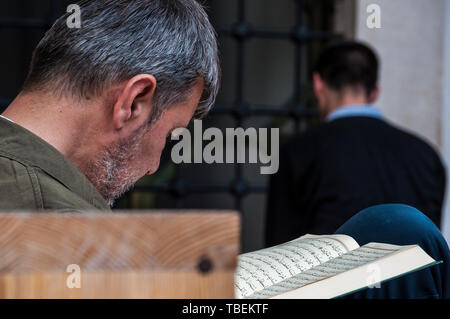 Sarajevo, Bosnia: a muslim man reading the Quran near a brother praying in the direction of Mecca outside the Gazi Husrev-beg Mosque (1532) Stock Photo