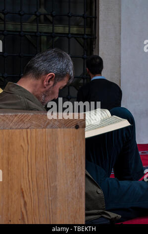 Sarajevo, Bosnia: a muslim man reading the Quran near a brother praying in the direction of Mecca outside the Gazi Husrev-beg Mosque (1532) Stock Photo