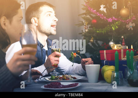 Family couple having christmas dinner with champagne and watching tv Stock Photo