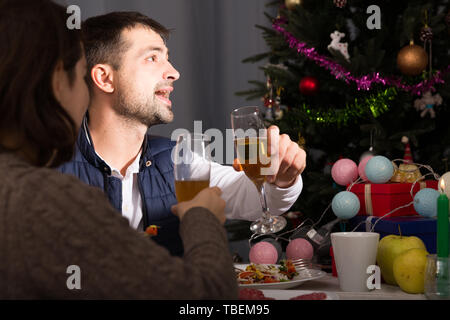 Family couple having christmas dinner with champagne and watching tv Stock Photo