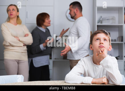 Sad desperate little boy during parents quarrel in home interior Stock Photo