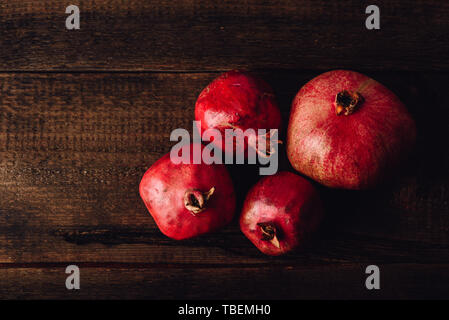Four ripe pomegranate on rustic wooden table Stock Photo