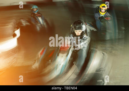 Group of male and females in helmets driving racing cars at kart track Stock Photo