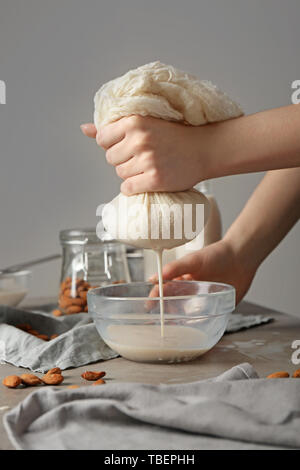 Woman making healthy almond milk in kitchen Stock Photo