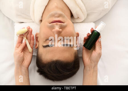 Man undergoing treatment with serum and having face massage in beauty salon Stock Photo