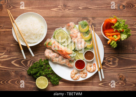 Plate with tasty spring rolls and sauces on wooden table Stock Photo