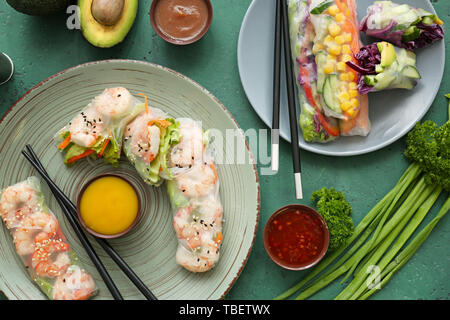 Tasty spring rolls and sauces on color table Stock Photo