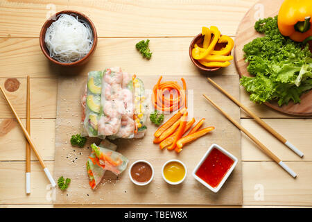 Tasty spring rolls with sauces on wooden table Stock Photo