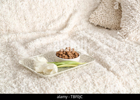Tray with pet food and flowers on sofa Stock Photo