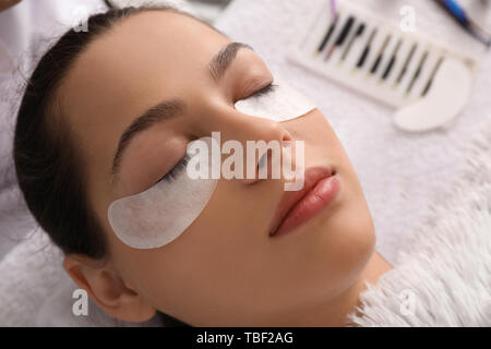 Young woman undergoing eyelash extension procedure in beauty salon Stock Photo