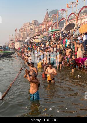 Hindu believers bath and perform ritual bath and puja prayers at ghats in the River Ganges, Varanasi, Uttar Pradesh, India Stock Photo