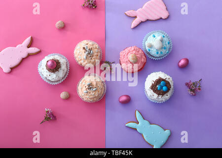 Tasty Easter cupcakes with cookies on color background Stock Photo