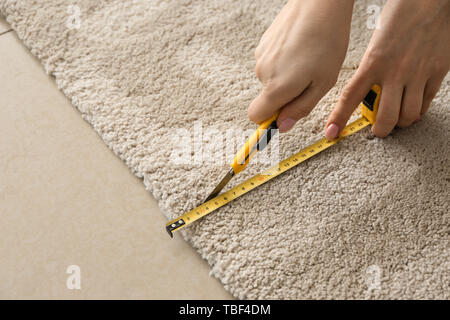 Woman with tape measure cutting carpet Stock Photo