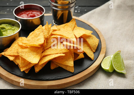 Board with tasty nachos and sauces on table Stock Photo