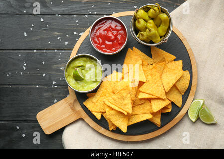 Board with tasty nachos and sauces on table Stock Photo