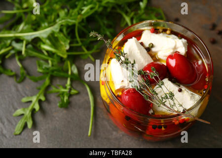 Glass jar with tasty feta cheese in olive oil on table Stock Photo