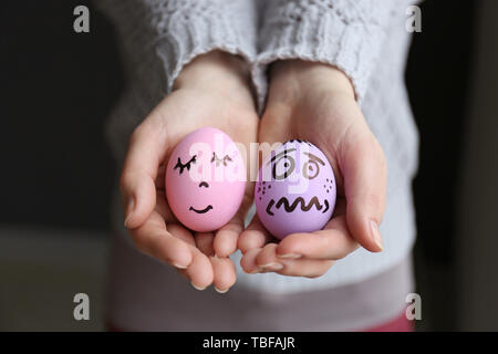 Woman holding Easter eggs with funny drawn faces, closeup Stock Photo