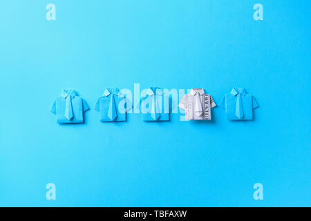 Origami shirt made of dollar banknote among paper ones on color background. Concept of uniqueness Stock Photo