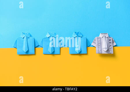 Origami shirt made of dollar banknote among paper ones on color background. Concept of uniqueness Stock Photo