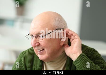 Senior man with hearing aid at home Stock Photo