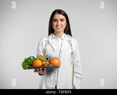 Portrait of female nutritionist with healthy products on light background Stock Photo