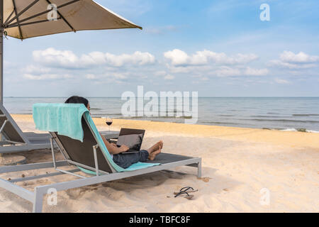 Young freelancer working on laptop by the beach on summer vacation Stock Photo