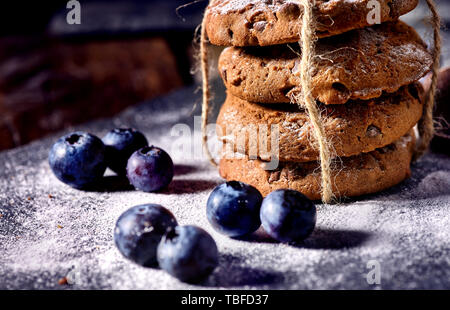 Bakers gonna bake. Serving food on slate. Oatmeal cookies biscuit with blueberry on dark tiles countrylike. Chocolate chip cookies tied with string sh Stock Photo