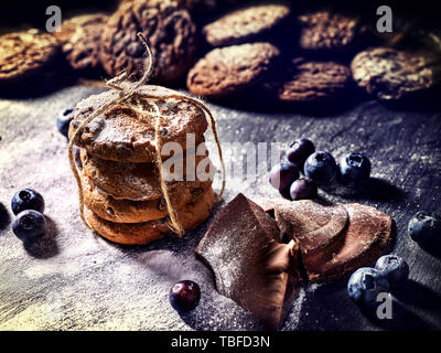 Bakers gonna bake. Serving food on slate. Oatmeal cookies biscuit with blueberry on dark tiles countrylike. Chocolate chip cookies tied with string sh Stock Photo