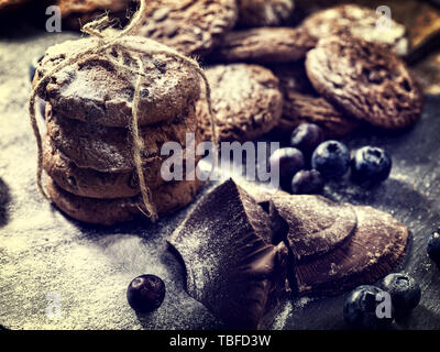 Bakers gonna bake. Serving food on slate. Oatmeal cookies biscuit with blueberry on dark tiles countrylike. Chocolate chip cookies tied with string sh Stock Photo