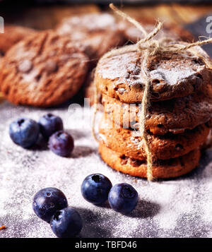 Bakers gonna bake. Serving food on slate. Oatmeal cookies biscuit with blueberry on dark tiles countrylike. Chocolate chip cookies tied with string sh Stock Photo