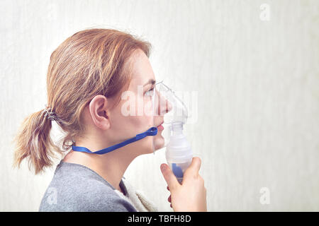 Woman is doing inhalation to relieve asthma symptoms with nebulizer chamber. Stock Photo