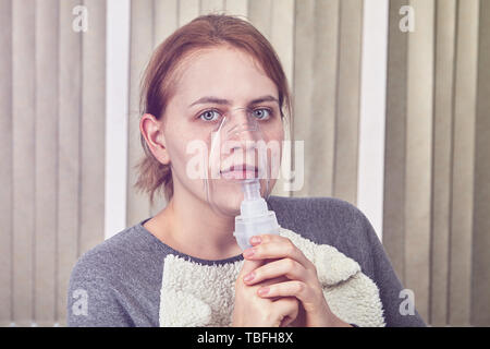 Girl is using nebulizer chamber, because she has lung inflammation and she is breathing through it. Stock Photo