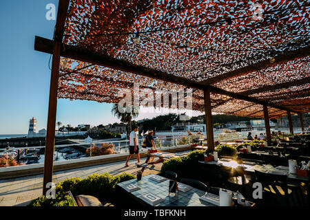 Cascais, Portugal - May 31, 2019: Ultra wide angle view of pedestrians at terrace overlooking Santa Marta Lighthouse and Museum in Cascais, Lisbon Stock Photo