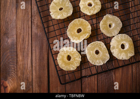 Grid with tasty dried pineapple on wooden table Stock Photo