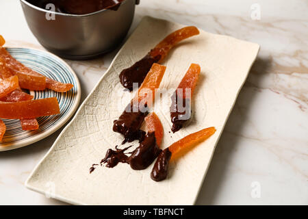 Tasty chocolate covered orange peels on light table Stock Photo
