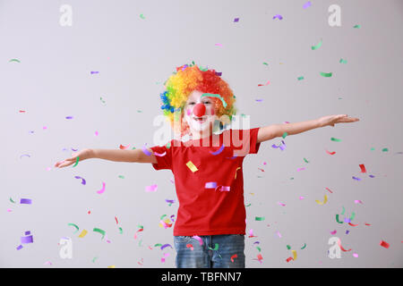 Little boy in funny disguise and falling confetti on light background. April fools' day celebration Stock Photo