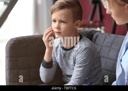 Female psychologist working with upset little boy in office Stock Photo