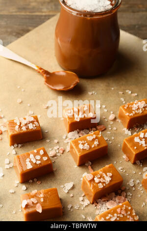 Tasty candies with salted caramel in jar on table Stock Photo