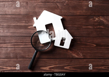 Models of house with magnifier on wooden table. Concept of earthquake Stock Photo