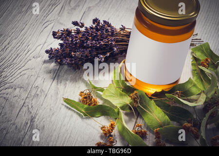 Honey in jar with lavender and linden flowers on vintage wooden background. Stock Photo