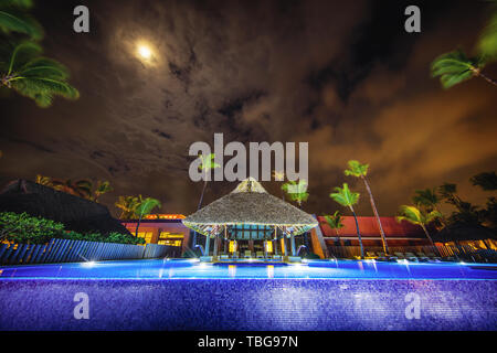 Tropical swimming pool and palm trees in luxury resort at night Stock Photo