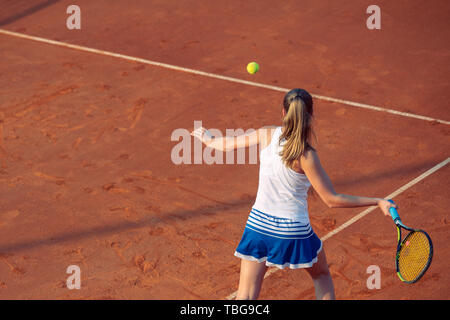 Young woman playing tennis on clay. Forehand. Stock Photo