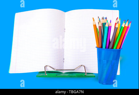 School notebook and colored pencils in a blue glass on a white background Stock Photo