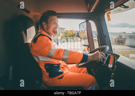 Garbage removal worker driving a dump truck  Stock Photo