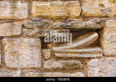 Church stone ornament fragments embedded in a Cotswold stone wall Stock Photo