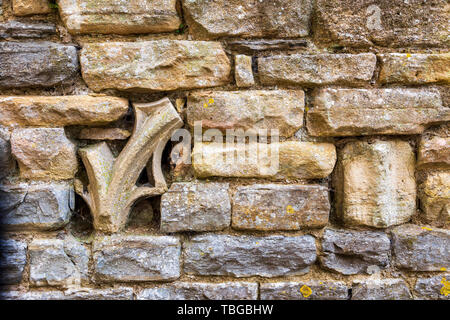 Church stone ornament fragments embedded in a Cotswold stone wall Stock Photo