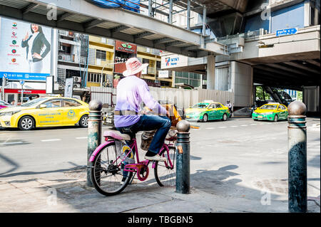 A lottery ticket seller travels through Bangkok on his bicycle selling tickets on Sukhumvit Rd. Thailand. Stock Photo