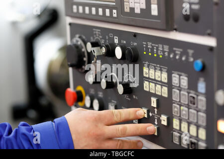 Engineer setup operation parameters of CNC lathe machine using buttons on the control panel. Selective focus. Stock Photo