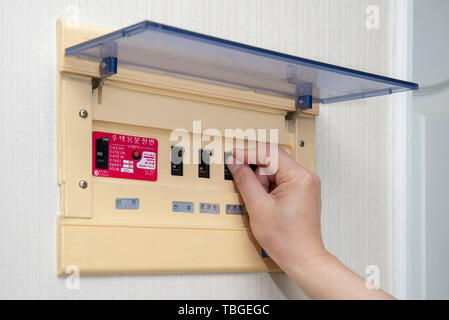 The electrician on hand opens circuit breaker board. Electrical Safety Concept. Stock Photo