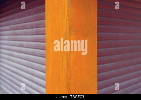 The corner of the building is of yellow painted boards and horizontal violet panels. Stock Photo